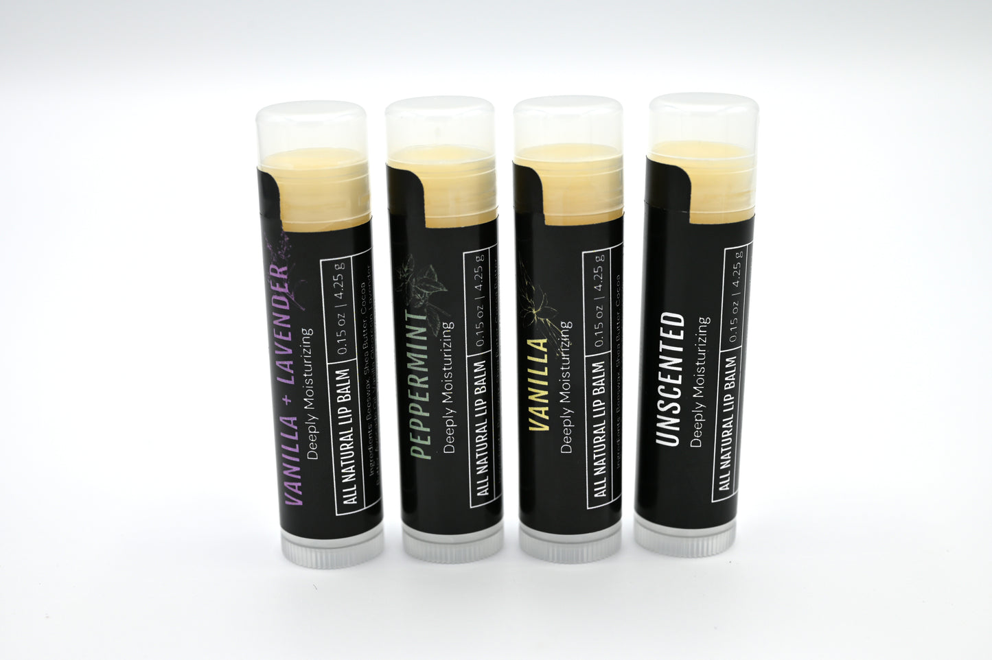 4 all natural lip balms with black labels standing upright in a line with a white background