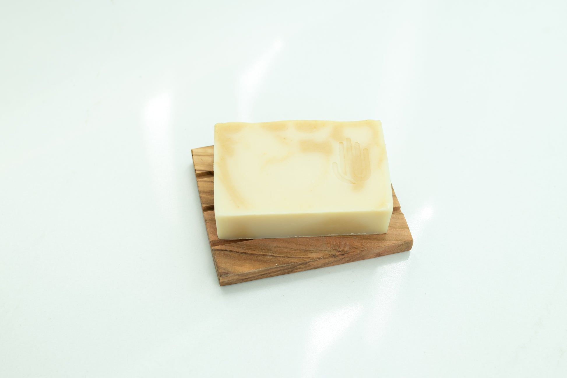 square white and yellow swirled soap placed on a wooden soap dish