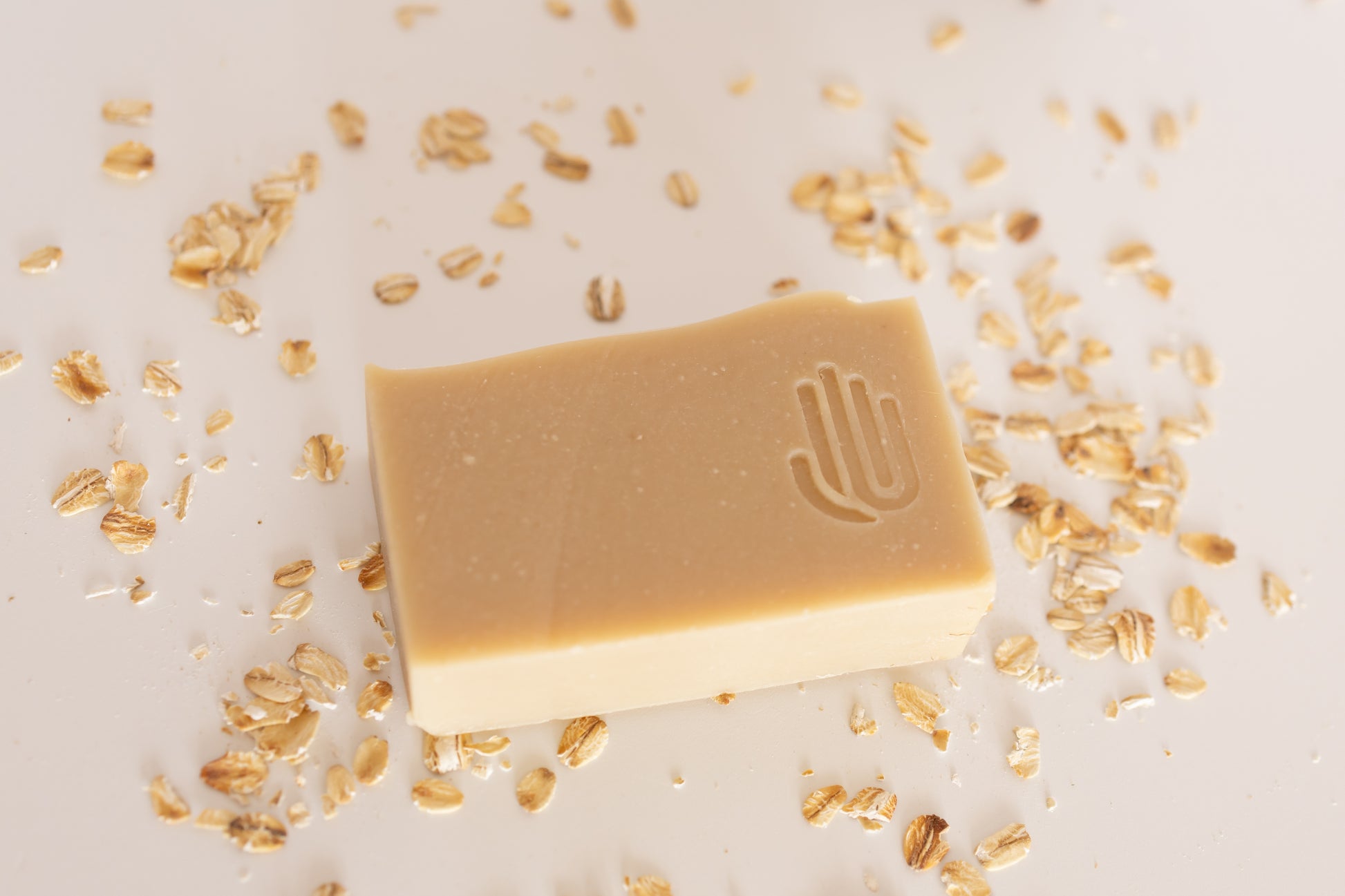 square tan colored soap with rolled oats scattered around