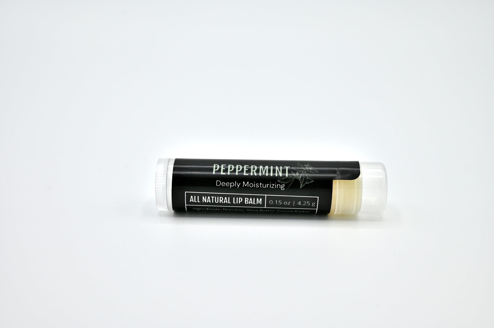 All natural peppermint lip balm with a black label and clear cap laying on its side with a white background