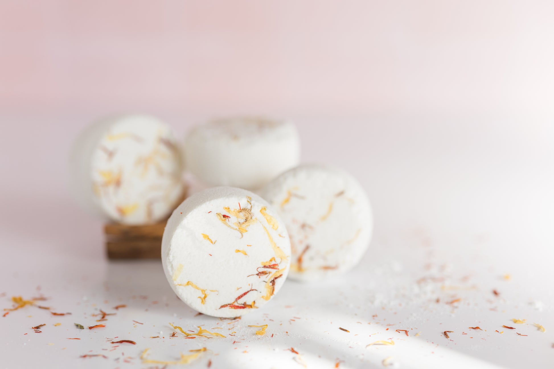 four citrus shower steamers on a wood tray with dried flowers scattered around