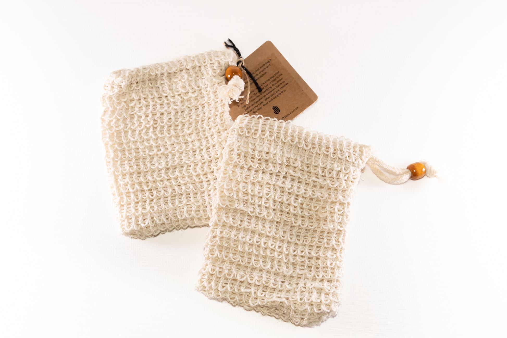 two natural sisal soap saver bags with wooden beads on the drawstring sitting on a white background