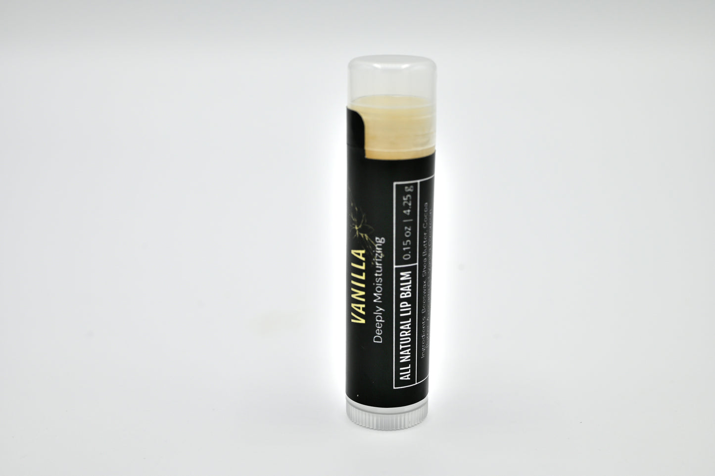 All natural vanilla lip balm with a black label and clear cap sitting upright with a white background