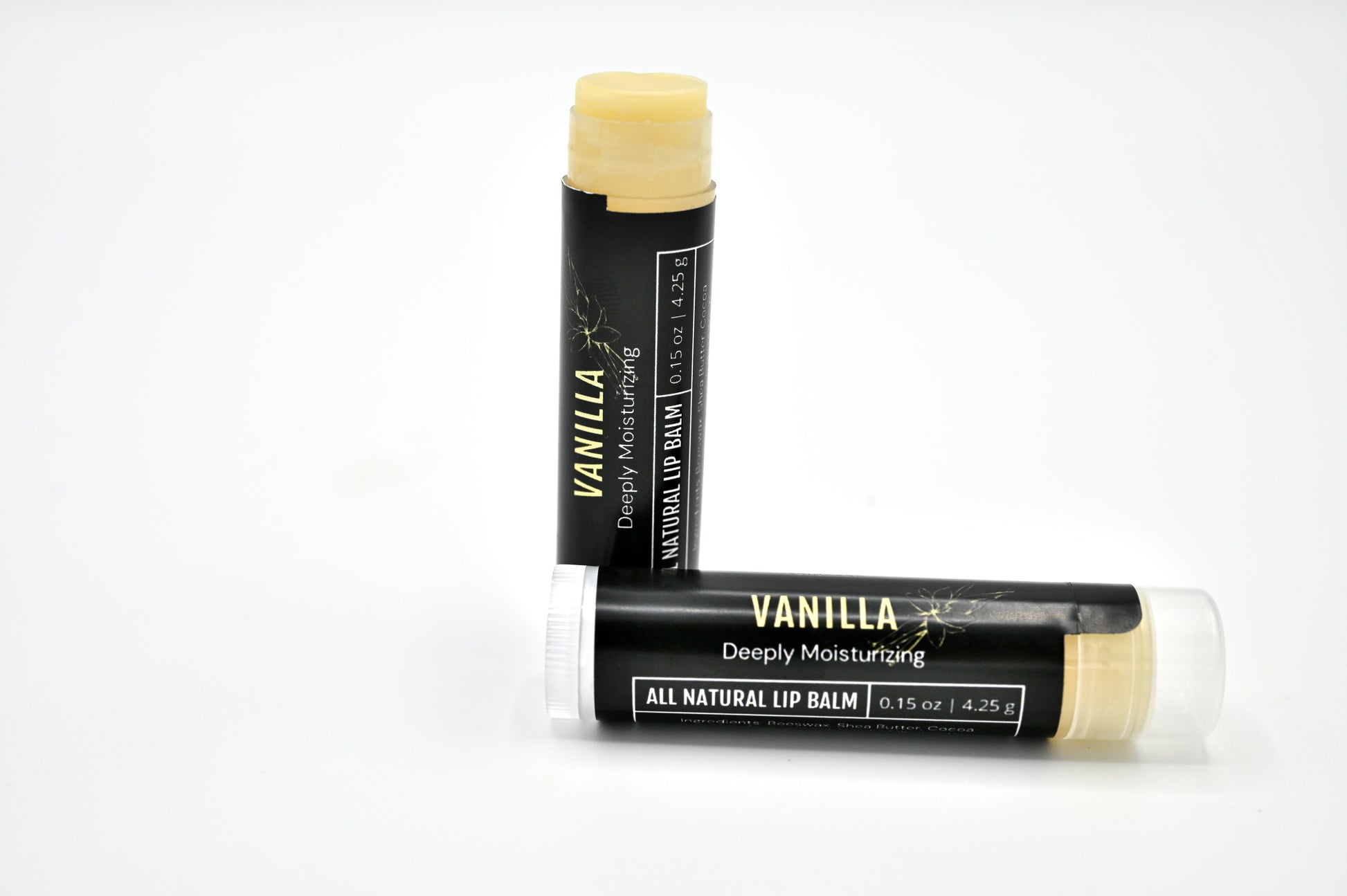 2 all natural vanilla lip balms with a black labels with one open showing a clear balm and sitting upright and one is sitting on its side closed behind the open tube of lip balm