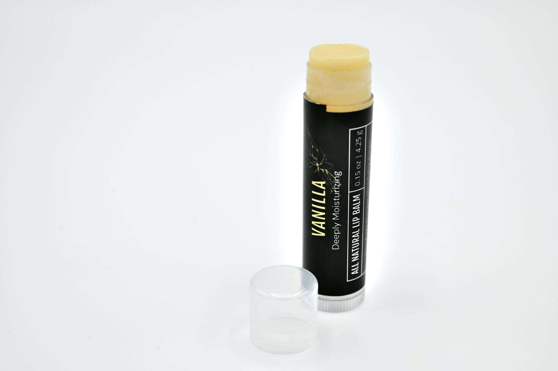 All natural vanilla lip balm with a black label with the container open showing a clear balm with a clear cap sitting to the side of the tube