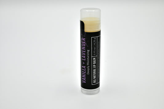 All natural vanilla and lavender lip balm with a black label and clear cap sitting upright with a white background